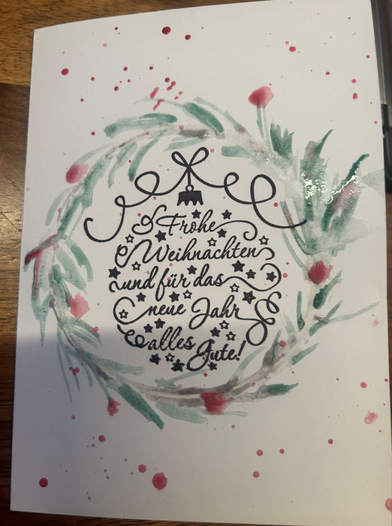 Handgemalte Weihnachtskarte mit Aquarellkranz und dem Schriftzug „Frohe Weihnachten und für das neue Jahr alles Gute“