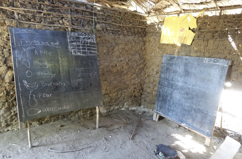 Erster Klassenraum der Madongoni Star Primary School aus Lehm mit zwei Schultafeln