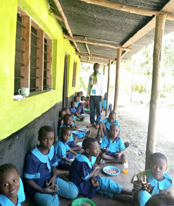 Das fertiggestellte Schulgebäude in Madongoni; die Kinder essen im Schatten der Veranda